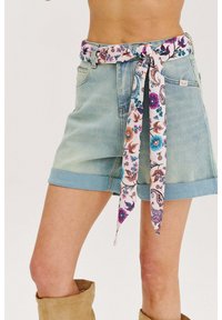 Džinsové šortky vo svetlých odtieňoch s vyrolovanými okrajmi, s kvetinovým opaskom v ružových, modrých a oranžových odtieňoch, ktorý je zaviazaný v páse.