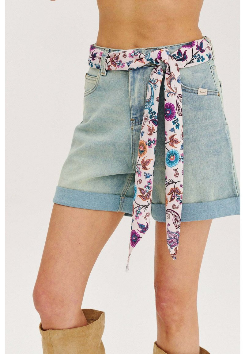 Džinsové šortky vo svetlých odtieňoch s vyrolovanými okrajmi, s kvetinovým opaskom v ružových, modrých a oranžových odtieňoch, ktorý je zaviazaný v páse.
