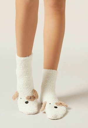 Witte pluizige sokken met een honden gezicht ontwerp, met tan accenten voor de oren en een zwarte neus, gewatteerde textuur en middenkuithoogte.