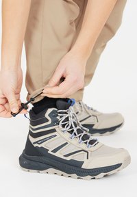 Bruine waterdichte wandelschoenen met zwarte en blauwe accenten; meshpanelen; gestreept ontwerp; vetersluiting met een toggle; duurzame rubberen zool.
