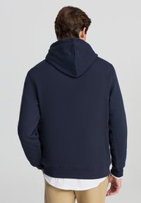 Felpa blu navy realizzata in tessuto morbido, con un ampio cappuccio, maniche lunghe e orlo a coste. Nessun logo o decorazione visibile.