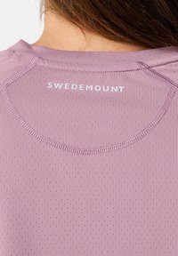 Licht paarse sportshirt met een ronde halslijn, mesh textuur en een bedrukt 'SWEDEMOUNT' logo op de achterkant van de nek.