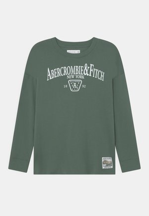 Dunkelgrünes Langarmshirt mit weißem Schriftzug "Abercrombie & Fitch New York 1892" und einem kleinen naturbezogenen Aufnäher am Saum.