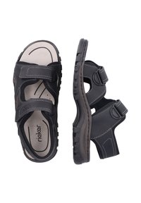 Des sandales noires à brides réglables, avec des semelles rembourrées et une semelle extérieure en caoutchouc texturé. Les détails cousus ajoutent du contraste et un motif.