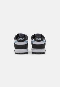Sneaker Nike neri e grigi con suola bianca, caratterizzati da un materiale liscio, dettagli blu chiaro e un logo rialzato sul tallone.