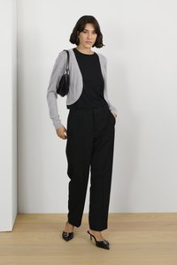 Gray long-sleeve cardigan over a black shirt, paired with black high-waisted trousers and pointed black heels. Simple, modern design.