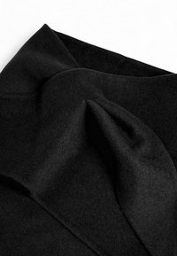 Black wool scarf featuring a soft texture, draped fabric with folds, and a smooth finish. No visible patterns or hardware details.