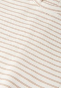 Top de tela a rayas en crema y beige con una textura suave y lisa. Presenta rayas horizontales y un escote sencillo y redondeado.