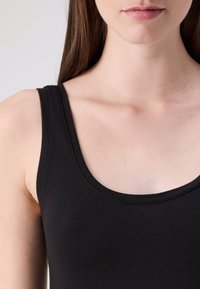 Czarna bluzka na ramiączkach wykonana z miękkiego materiału, z okrągłym dekoltem i wąskimi ramiączkami, dopasowany krój, gładka faktura i minimalne detale szwów.