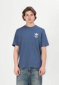 Mørkeblå bomulds t-shirt med korte ærmer, prydet med et hvidt logo på brystet. Skåret i en afslappet pasform med rund halsudskæring.