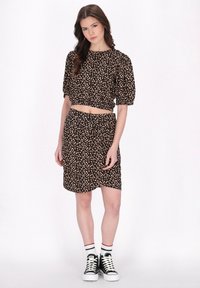 Svart blommig crop top med puffärmar, matchad med en omslagskjol. Stylad med svarta högskaftade sneakers och vita randiga strumpor.