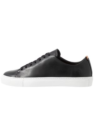 Czarny, niski skórzany sneaker z czarnymi sznurówkami, białą gumową podeszwą i brązową pętelką przy pięcie, widziany z boku.