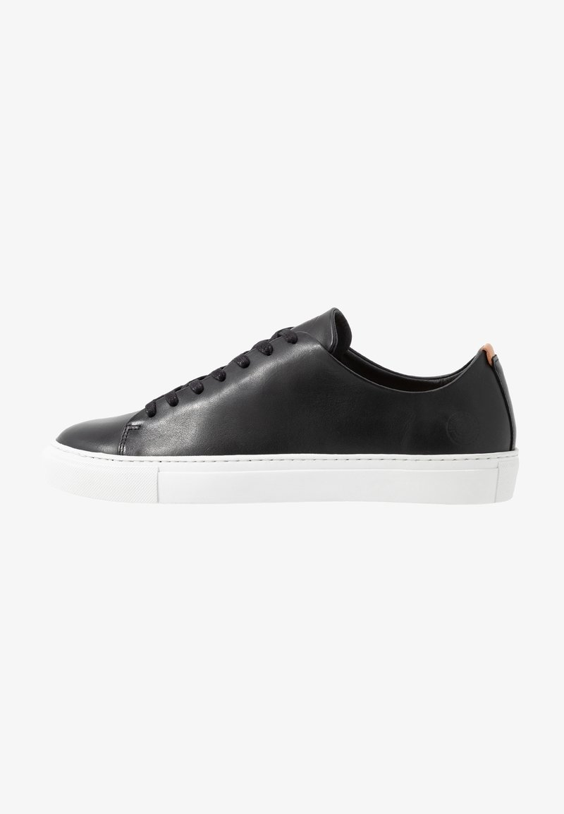 Baskets basses en cuir noir avec lacets noirs, semelle blanche en caoutchouc et languette marron au talon, vues de côté.