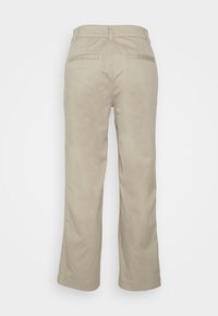 Pantalons en coton beiges avec une coupe droite, deux poches arrière et des surpiqûres décoratives. Texture lisse avec une finition soignée.