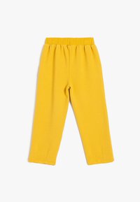 Gelbe Ripp-Hosen mit elastischem Bund, geradem Schnitt und Saumdetails. Weicher Stoff mit subtilen Linien im gesamten Material.