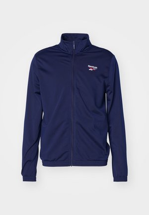 Jūras spēku zip-uppa jakas, izgatavotas no gludas auduma ar augstu apkakli, ar mazu balto un sarkano Reebok logo kreisajā krūtī.