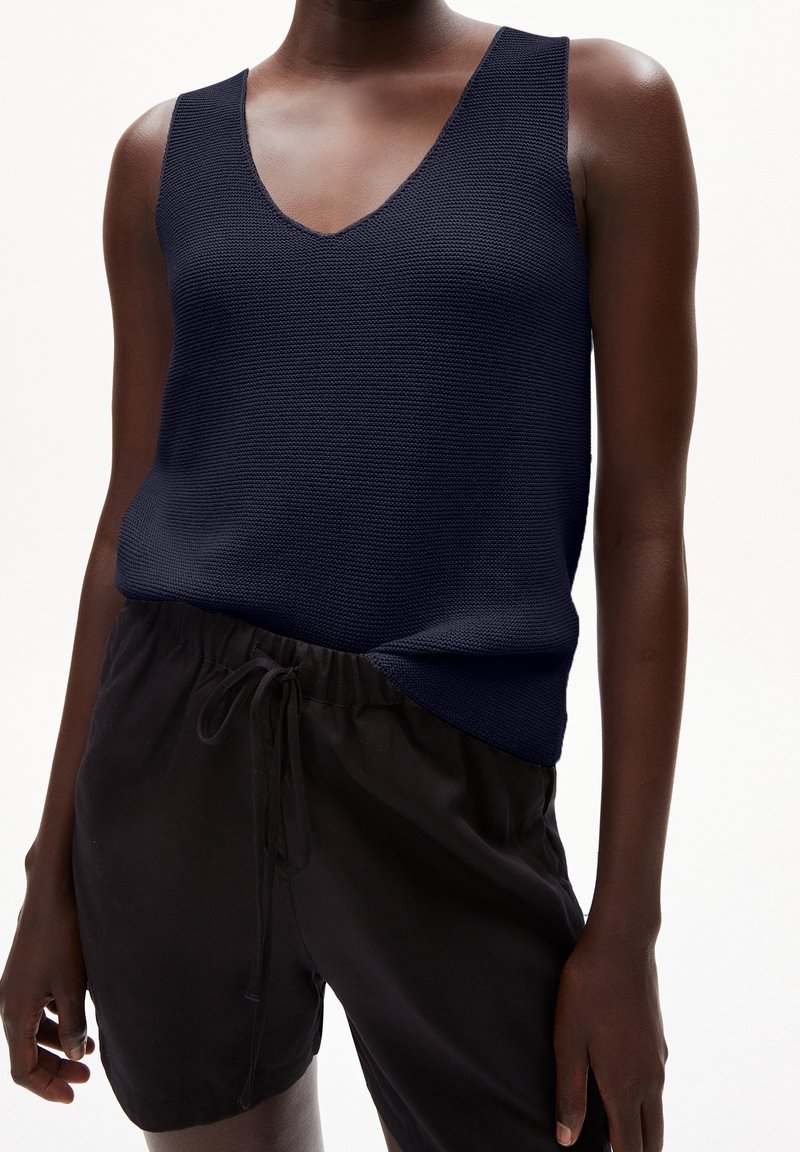 Débardeur tricoté marine avec un col en V et de larges bretelles, associé à un short noir à cordon de serrage. Le tissu a une finition texturée.