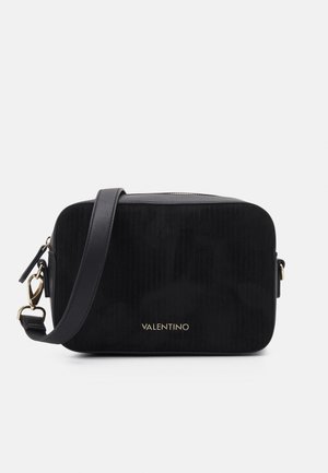 Musta suorakaiteenmuotoinen Valentino-laukkukoru säädettävällä hihnalla ja kullanvärisillä metalliosilla valkoisella taustalla.