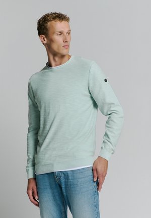 Muntgroene gebreide sweatshirt met lange mouwen, ronde hals, ribgebreide manchetten en zoom. Bevat een klein zwart logo op de linker mouw.