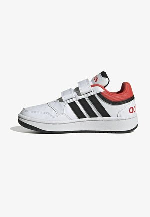 White athletic shoes with black stripes, red accents on the heel and tongue, Velcro straps, and a textured rubber sole.
