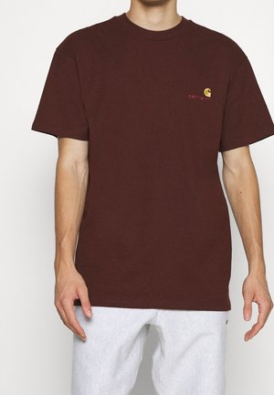 T-shirt in cotone color marrone con colletto a giro e maniche corte. Presenta un piccolo logo giallo Carhartt sul petto e un orlo dritto.