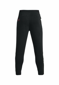 Schwarze, taillierte Sporthose mit elastischem Bund, Reißverschlusstaschen und einem kleinen roten Logo nahe der Hüfte, von hinten gezeigt.