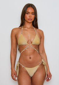 Gouden bikini-set met driehoekige cups, versierd met kralen en bedels. Heeft verstelbare nek- en zijbanden, glinsterende textuur.