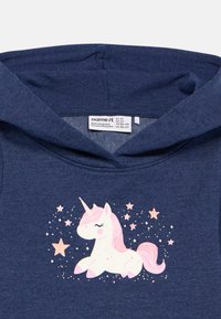 Vaikiška tamsiai mėlyna džemperis su rožine ir balta vienaragio iliustracija, apsupta rožinių žvaigždžių ir blizgučių priekyje.