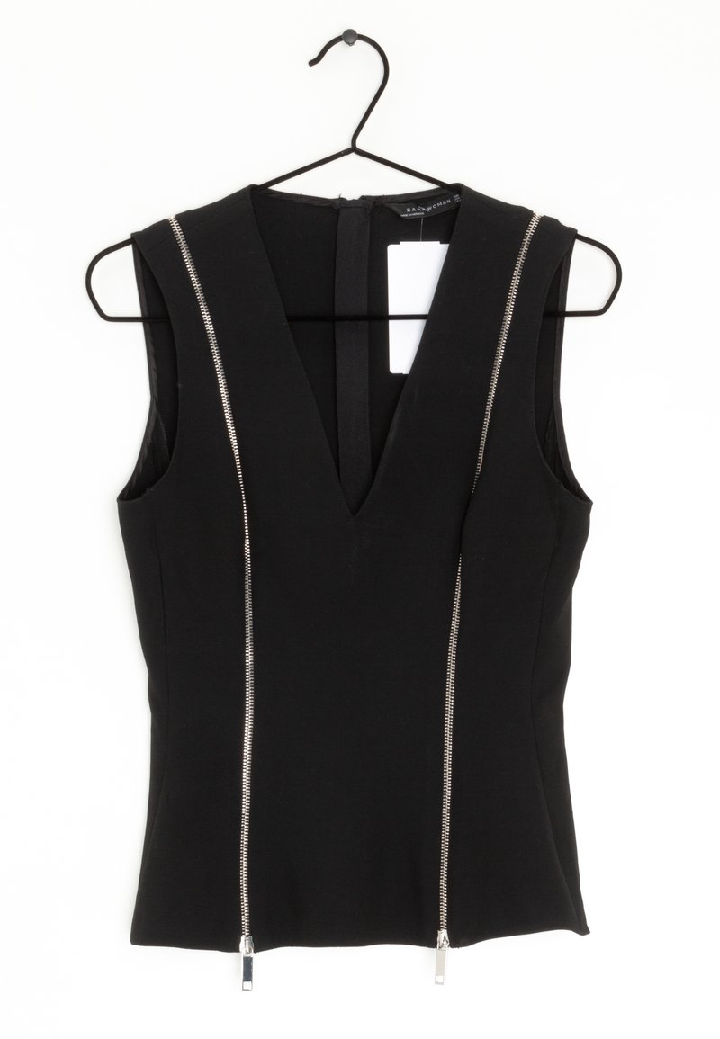 Zwarte mouwloze top met een diepe V-hals en twee zilveren ritsaccenten aan de voorkant. Gemaakt van een gladde stof, is het aansluitend met een verborgen rits aan de achterkant.