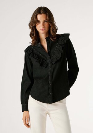 Black denim shirt with ruffled collar, snap-button closure, and decorative studs. Long sleeves with buttoned cuffs. Fitted design.