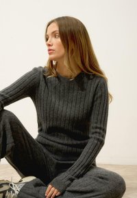 Szary sweter z prążkowanej dzianiny oraz pasujące spodnie, z długimi rękawami i okrągłym dekoltem. Miękka tekstura i wygodne dopasowanie.