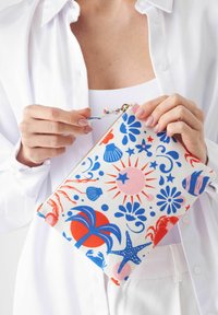 Kleurrijke canvas etui met oceaanthema patronen, waaronder sterren, schelpen en zeedieren, met een gouden rits en een handband.