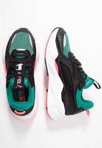 Svarta sneakers med mesh och texturerade gröna detaljer, vit och korallfärgade detaljer på sulan, med snörning och vadderad krage.