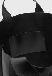 Mala de ombro preta com exterior macio e texturizado e um remendo interior em pele preta. Apresenta alças robustas em tecido e um design minimalista.