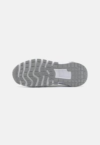 Sole in gomma grigia con una texture ondulata, motivo del battistrada segmentato e accenti bianchi lungo i bordi. Progettata per offrire aderenza e durata.