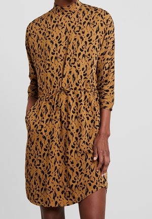 Brązowa sukienka z czarnym abstrakcyjnym zwierzęcym nadrukiem, z wysokim kołnierzem, rękawami za łokieć, przednimi kieszeniami oraz wiązaniem w talii. Gładka faktura materiału.