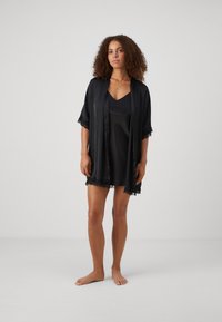 Ensemble de lingerie en satin noir avec une robe kimono assortie ornée de dentelle. Le tissu a une texture lisse et un design élégant.