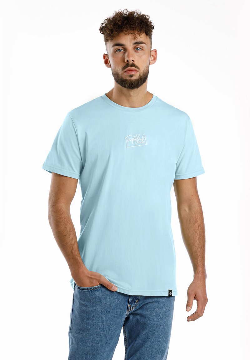 Helles blaues Baumwoll-T-Shirt mit kurzen Ärmeln, Rundhals und einem weißen Grafiklogo auf der Brust. Getragen mit blauen Jeans.