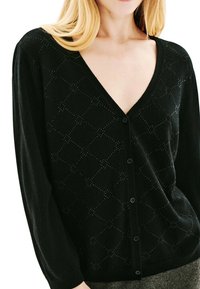 Cardigan noir en tricot avec un décolleté en V profond, des manches longues, des motifs en losange et une fermeture par boutons sur le devant. Texture douce.