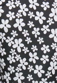 Tecido preto com um padrão floral branco, apresentando formas e tamanhos de flores variados, destacando uma trama texturizada e contornos distintos.