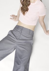 Rosa kortärmad skjorta i croppad modell som kombineras med grå randiga byxor med en slät textur och skräddarsydd passform.