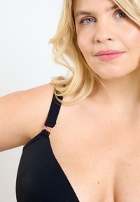 Svart bh med en slät yta, som har en V-ringad design, justerbara band och dekorativ roséguldsspärr vid kopplingen.