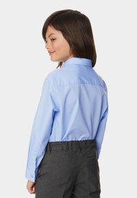 Lichtblauw overhemd met lange mouwen, een puntkraag, knoopmanchetten en een zachte stof. Gepaard met grijze broek met een achterzak.