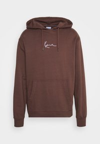 Felpa con cappuccio marrone realizzata in tessuto morbido, dotata di una tasca frontale e testo ricamato bianco sul petto. Vestibilità classica con polsini a costine.