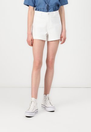 Hvite denim shorts med høy midje, med knappelukking og beltehemper, kombinert med hvite høye sneakers.