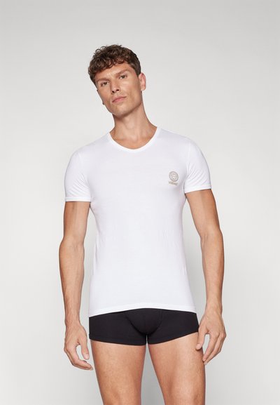 Weißes Baumwoll-T-Shirt mit kurzen Ärmeln und V-Ausschnitt. Auf der Brust befindet sich ein goldenes Versace-Logo. Glatte Textur, taillierte Passform.
