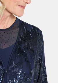Marineblaues Paillettensakko mit strukturiertem Muster, verziert mit kleinen Polka Dots und einem transparenten Überzug, ausgestattet mit einem runden Ausschnitt und einer glatten Basisschicht.