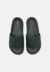 Sandales en caoutchouc de couleur vert foncé avec une sangle texturée ornée de motifs géométriques, une semelle intérieure rembourrée et une semelle en caoutchouc pour une meilleure adhérence.