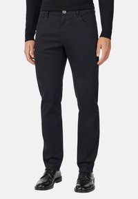 Jeans negros de corte ajustado hechos de una mezcla de algodón, con cinco bolsillos, trabillas para cinturón, cierre de botón y una textura suave.