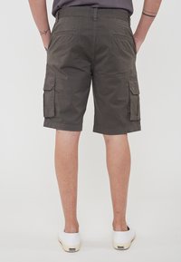 Pantaloni cargo grigi con tasche laterali, una vestibilità rilassata e una texture liscia, abbinati a sneaker bianche basse.